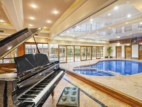 a mansion with a piano and a swimming pool at Entire Maggie's Guesthouse - free cinema, pool, spa, tennis court, karaoke, more! in Warrandyte