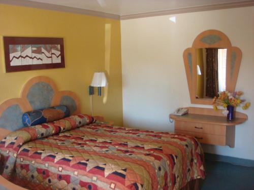 a hotel room with a bed and a mirror at Economy Inn Los Banos in Los Banos