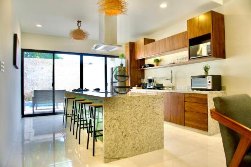 a kitchen with a counter and stools in a room at Casa árbol 350 MBS in Mérida