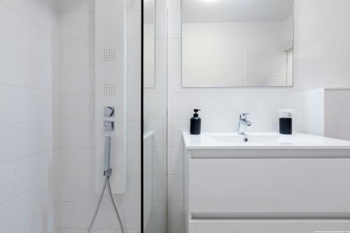 a white bathroom with a sink and a shower at Amantes del Mar, Heated pool in Costa Del Silencio