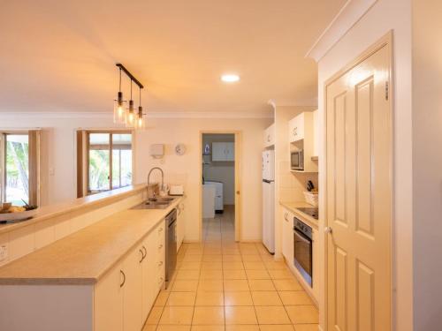 a large kitchen with white cabinets and a hallway at Peaceful 4B2B Sweet Home w Backyard at Springfield in Springfield Lakes