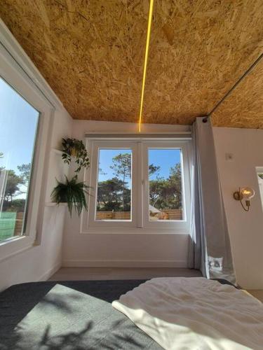 a bedroom with two windows and a bed in it at Cozy tiny house - Where the Sea meets the Florest in São João das Lampas