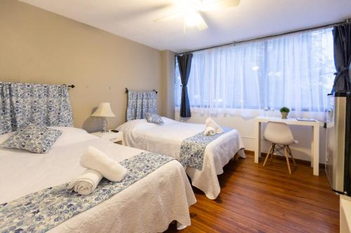 a bedroom with two beds and a desk and a window at Satya Suites & Portal San Angel Flats in Mexico City