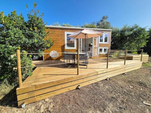 a wooden deck with a table and an umbrella at Cozy tiny house - Where the Sea meets the Florest in São João das Lampas