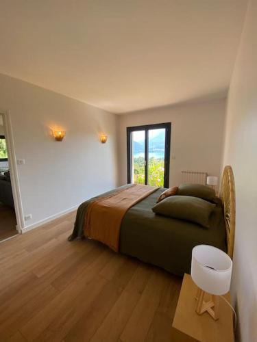 une chambre avec un grand lit et une fenêtre dans l'établissement Les Rochers du lac, à Cessenaz