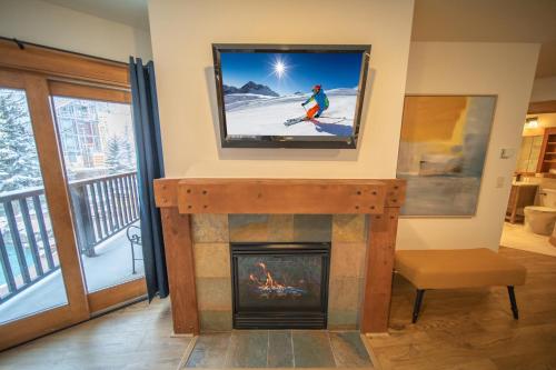 a living room with a tv above a fireplace at Springs 8838 by SummitCove Lodging in Keystone
