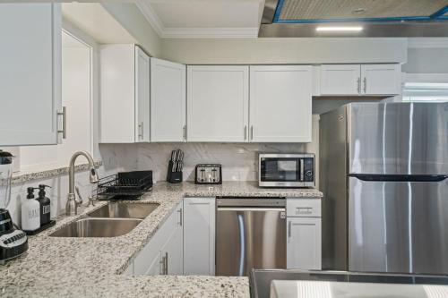 a kitchen with white cabinets and a stainless steel refrigerator at Amazing 4BR 2BA Winter Home with Pool & Game-Movie Room in Texas City