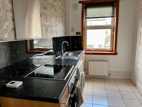 a kitchen with a sink and a stove top oven at Charming Seaside home Sleeps 4 with free parking in Broughty Ferry