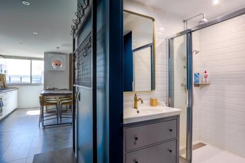 une salle de bain avec un lavabo et une douche avec un miroir dans l'établissement Lyon Premium - Happy 70's, à Villeurbanne