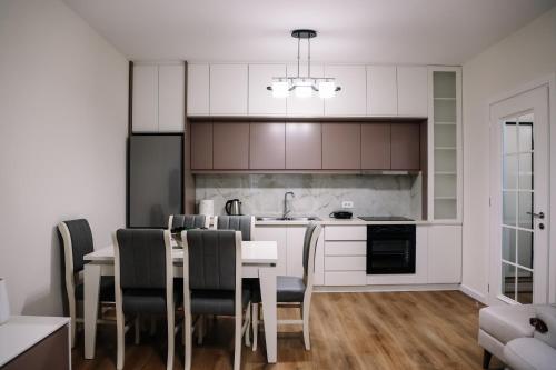 a kitchen with a table and chairs and a kitchen with white cabinets at Oasis Apartment Korce in Korçë
