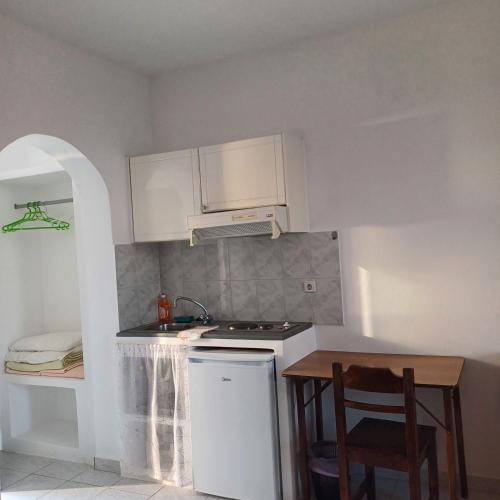 a small kitchen with a stove and a table at Lofos Studios in Agios Prokopios
