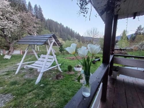 a porch with a chair and flowers in a yard at Тихий Куточок in Verkhovyna