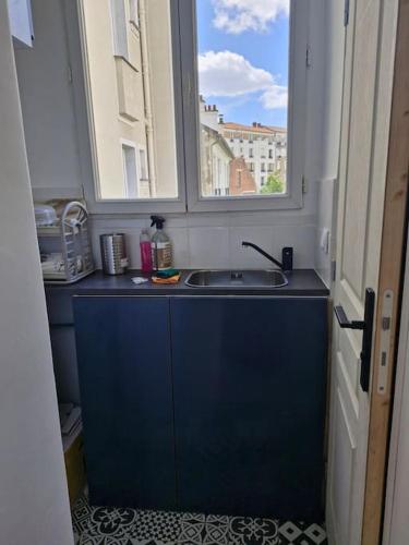 une cuisine avec un évier et une fenêtre dans l'établissement Studio meublé, à Asnières-sur-Seine