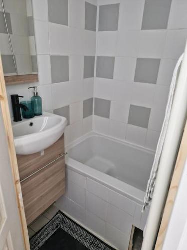 La salle de bains blanche est pourvue d'un lavabo, d'une baignoire et d'une baignoire. dans l'établissement Studio meublé, à Asnières-sur-Seine