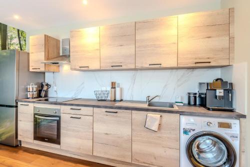 a kitchen with wooden cabinets and a washing machine at Les Chants de l'Eau avec balnéothérapie in Thonon-les-Bains