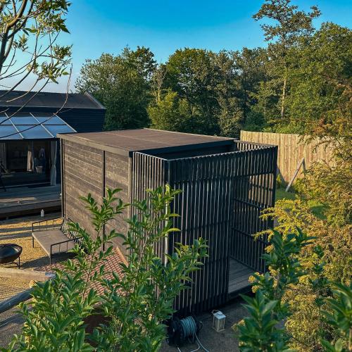 a small black building in a yard with trees at Cabin Westerwald Sauna, 5G Internet, E-Ladesäule in Niederdreisbach