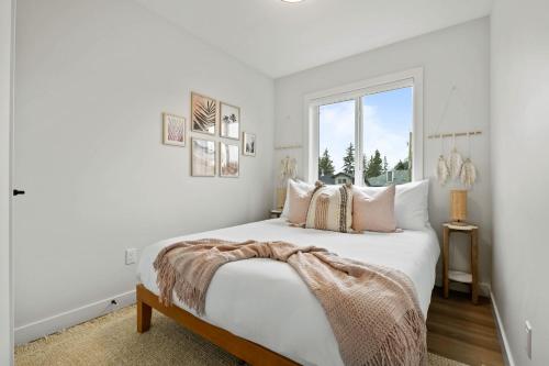a white bedroom with a large bed and a window at The Promenade I Patio and BBQ I Fire pit I Sleep 9 in Sylvan Lake