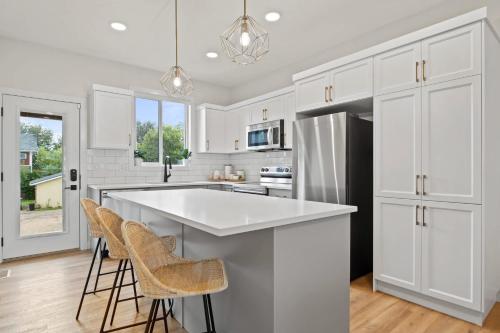 a kitchen with white cabinets and a kitchen island with stools at The Promenade I Patio and BBQ I Fire pit I Sleep 9 in Sylvan Lake