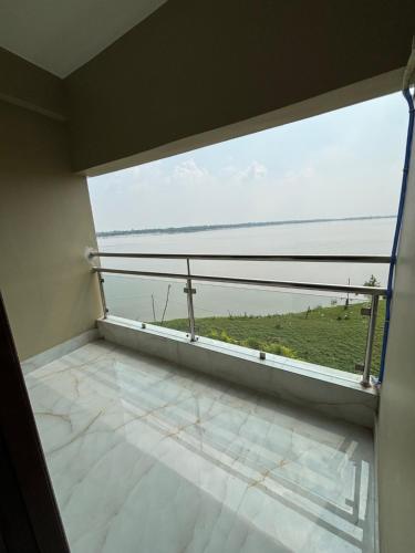 a room with a balcony with a view of the ocean at ICHHAMATI HOTEL AND RESTAURANT in Hāsnābād
