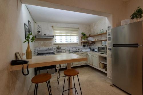 a kitchen with a refrigerator and a table and stools at Casa Itza in Mérida