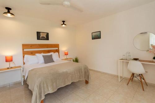 a bedroom with a bed and a desk and a mirror at Casa Itza in Mérida