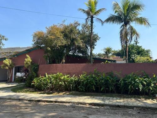 a house with palm trees and a fence at Casa Calú in Guarujá