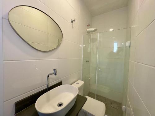 a bathroom with a sink and a mirror and a toilet at Casa Calú in Guarujá