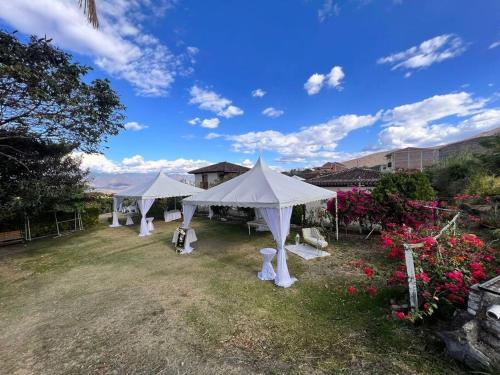 a row of white tents in a yard with flowers at Beautiful Country House in Loja