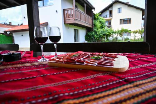 a table with two glasses of wine on a red table cloth at Къща Александра 2 in Dobrinishte