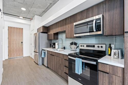 a kitchen with stainless steel appliances and wooden cabinets at Downtown beauty-PoolHotTubGym-near SaltPalace-View in Salt Lake City