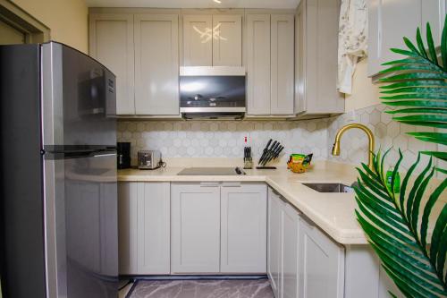 a kitchen with white cabinets and a stainless steel refrigerator at Heart of Ocho Rios-Free Beach Acess-King Bed-Pool-Free Parking-Gated Complex-Free Wifi 100Mbps in Ocho Rios