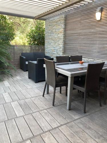 un patio avec une table, des chaises et un canapé dans l'établissement Maison vue mer à-5 minutes DE LA VIEILLE VILLE DE PORTO-VECCHIO, à Porto-Vecchio