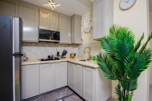 a kitchen with white cabinets and a green plant in it at Heart of Ocho Rios-Free Beach Acess-King Bed-Pool-Free Parking-Gated Complex-Free Wifi 100Mbps in Ocho Rios