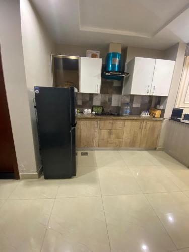 a kitchen with a black refrigerator and white cabinets at HOME DEALS appartment in Darwāla