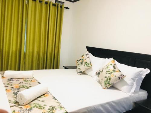 a bedroom with a white bed with pillows and a green curtain at Bracedale Estate in Kegalle