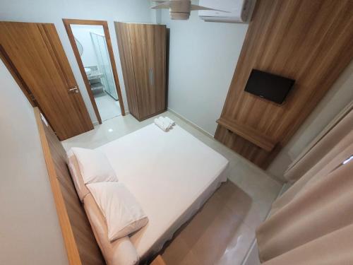 a small room with a white bed and a mirror at Estudio Imperatriz in Aracruz