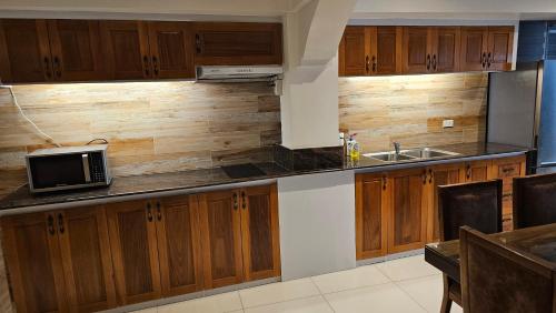 a kitchen with wooden cabinets and a microwave at Lydia's House in Kaputian