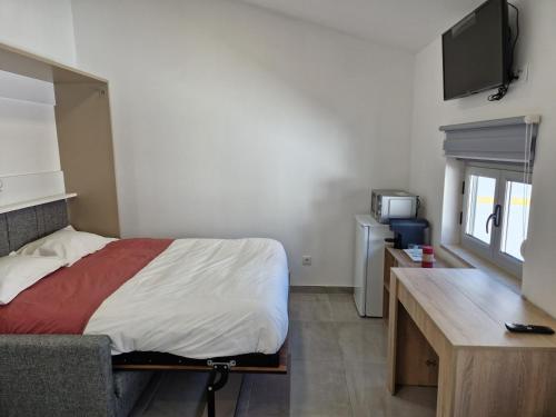 a bedroom with a bed and a desk and a tv at Escapada Magica in São Martinho do Porto