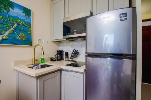 a kitchen with a stainless steel refrigerator and a sink at Center of Ocho Rios-Beachfront Studio-Free Beach Access-Pool-Free Parking-Gated Complex-Free Wifi 100Mbps in Ocho Rios