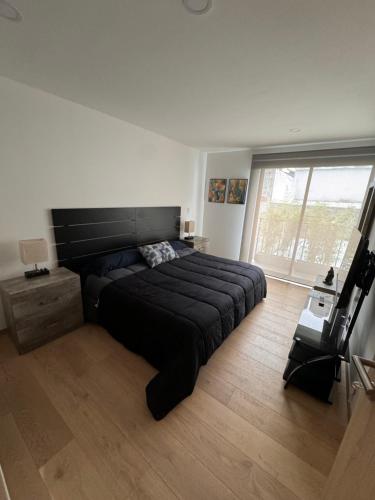 a bedroom with a black bed and a large window at Hermoso departamento en el corazón de Condesa in Mexico City