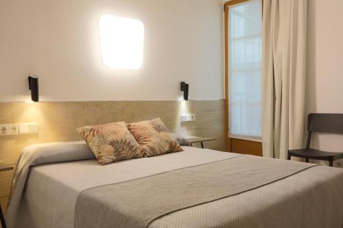 a bedroom with a bed with a light on the wall at Hostal Castilla II Puerta del Sol in Madrid