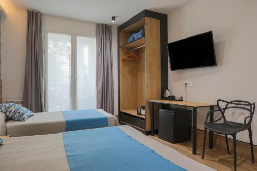 a hotel room with a bed and a desk and a television at Hostal Castilla II Puerta del Sol in Madrid