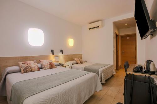 a hotel room with two beds and a flat screen tv at Hostal Castilla II Puerta del Sol in Madrid