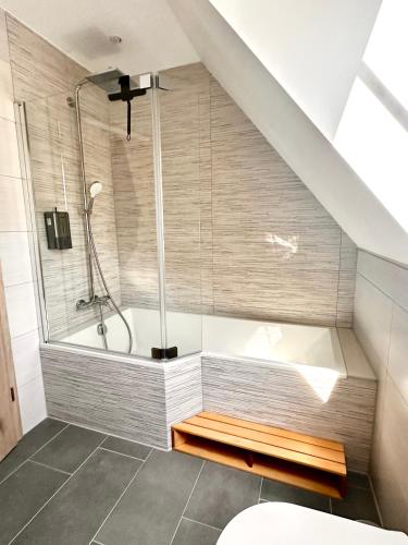 La salle de bains est pourvue d'une douche et d'une baignoire sous un escalier. dans l'établissement Duplex confort exceptionnel hyper centre calme sans vis à vis parking vue jardin, à Haguenau