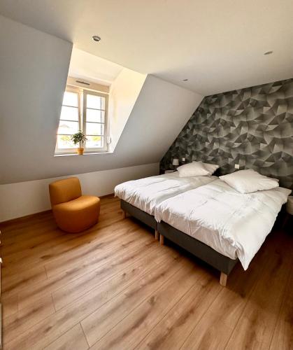 une chambre avec un grand lit et une chaise dans l'établissement Duplex confort exceptionnel hyper centre calme sans vis à vis parking vue jardin, à Haguenau