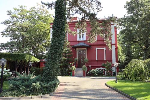 a red house with a large ivy covered tree at Willa Impresja Hotel i Restauracja in Pabianice