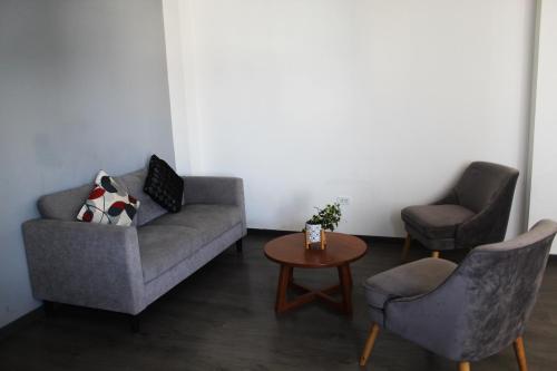 a living room with two chairs and a couch and a table at Basadre Apart Hotel in Tacna