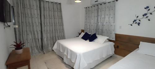 a bedroom with a white bed and a television at Pousada Filhos da Canastra in Vargem Bonita