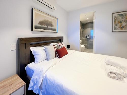 a bedroom with a large white bed with pillows at Box Hill Central Sky One Apartment in Box Hill