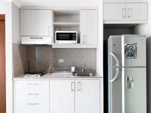 a kitchen with white cabinets and a white refrigerator at Depa de lujo con piscina y jacuzzi in Guayaquil